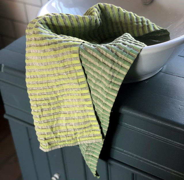 Glashandduk i linne från Växbo Lin i gröna och gråa ränder som en person använder för att torka händerna med